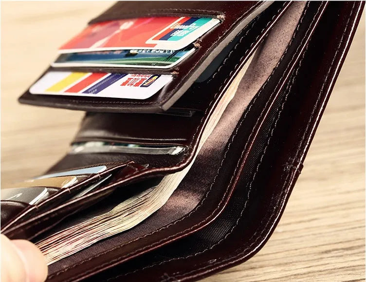 Men's black full-grain leather bifold wallet open, showing eight card slots and a zipped coin pocket.