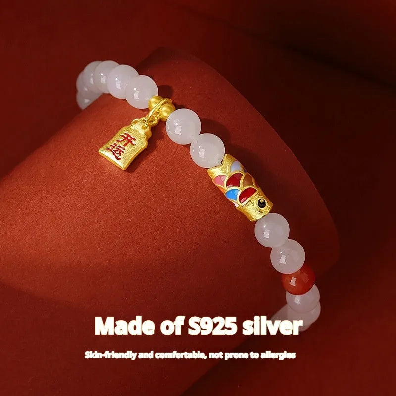 Close-up of a sterling silver bracelet with a carved green Hetian jade koi fish charm.
