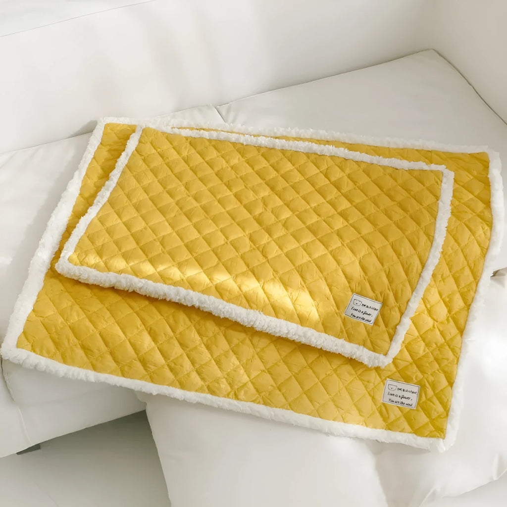 Quilted blue cloth pet blanket for cats, shown on a pet bed.