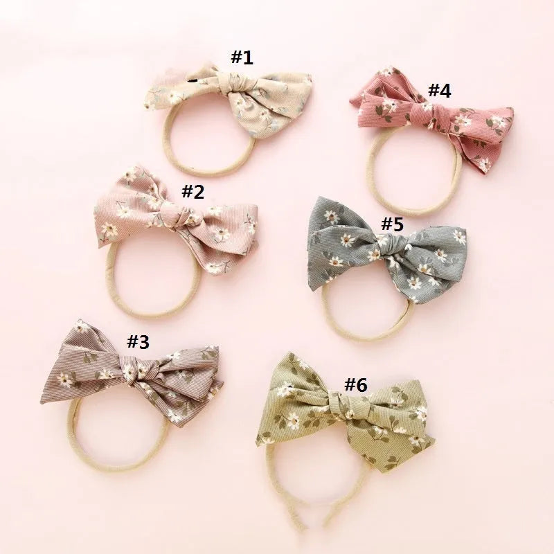 Children's cloth hair band with a white knotted bow, shown against a colour swatch background.
