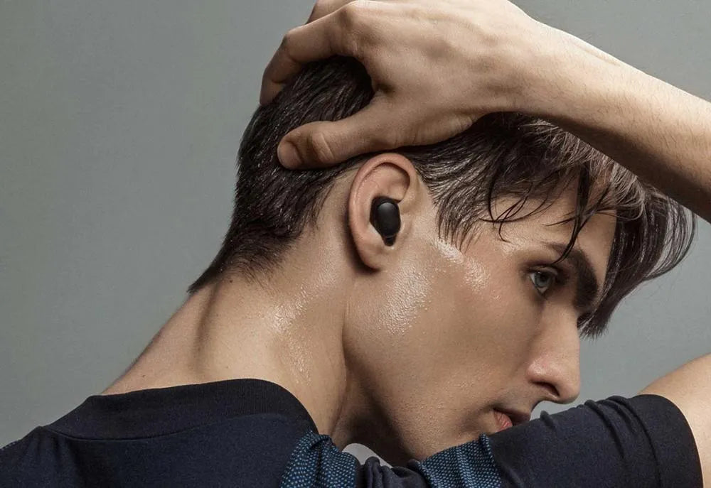 Black Redmi AirDots true wireless earbuds next to their compact charging case.