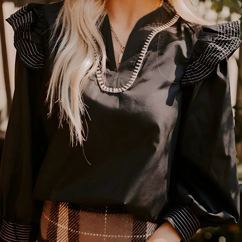 Black women's V-neck long sleeve blouse with ruffle trim and contrast stitching detail.