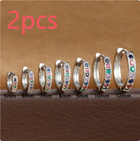Gold, rose gold, and silver circle-shaped perforated stud earrings on a plain background.