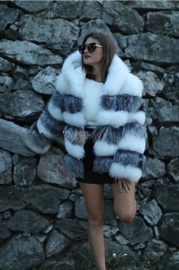 A woman wearing a loose-fitting artificial fur coat with a hood, in a street fashion style.