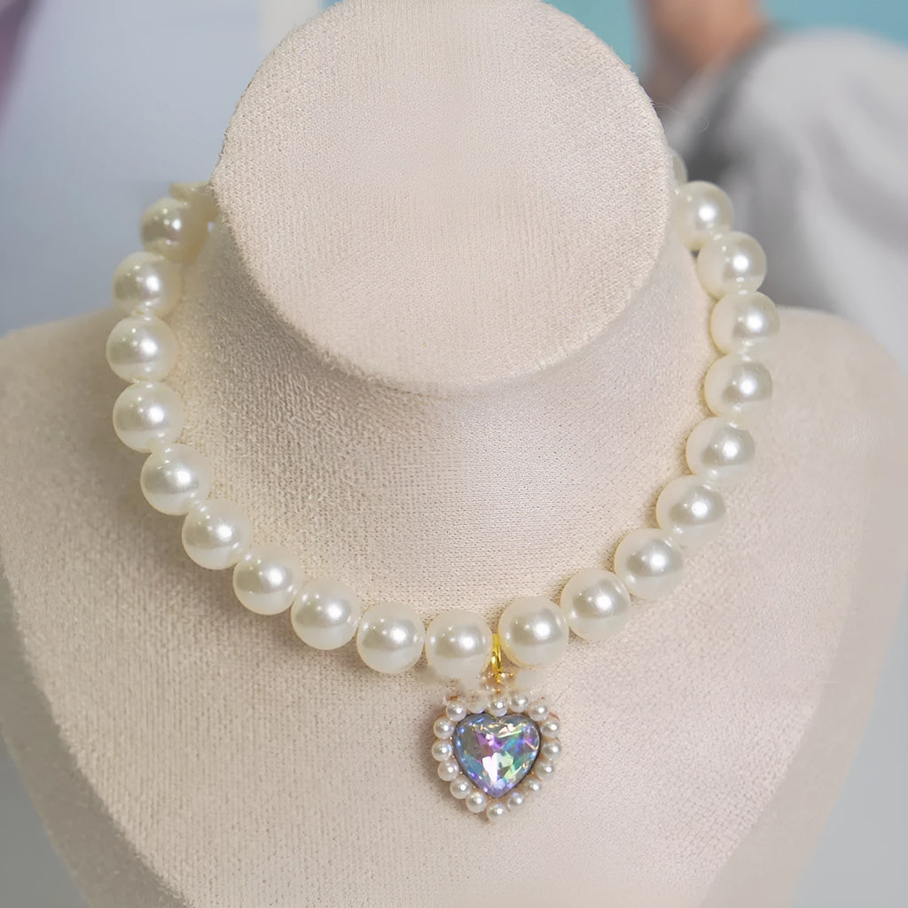 Pearl necklace cat collar with heart-shaped gem charm in various colours on a white background.