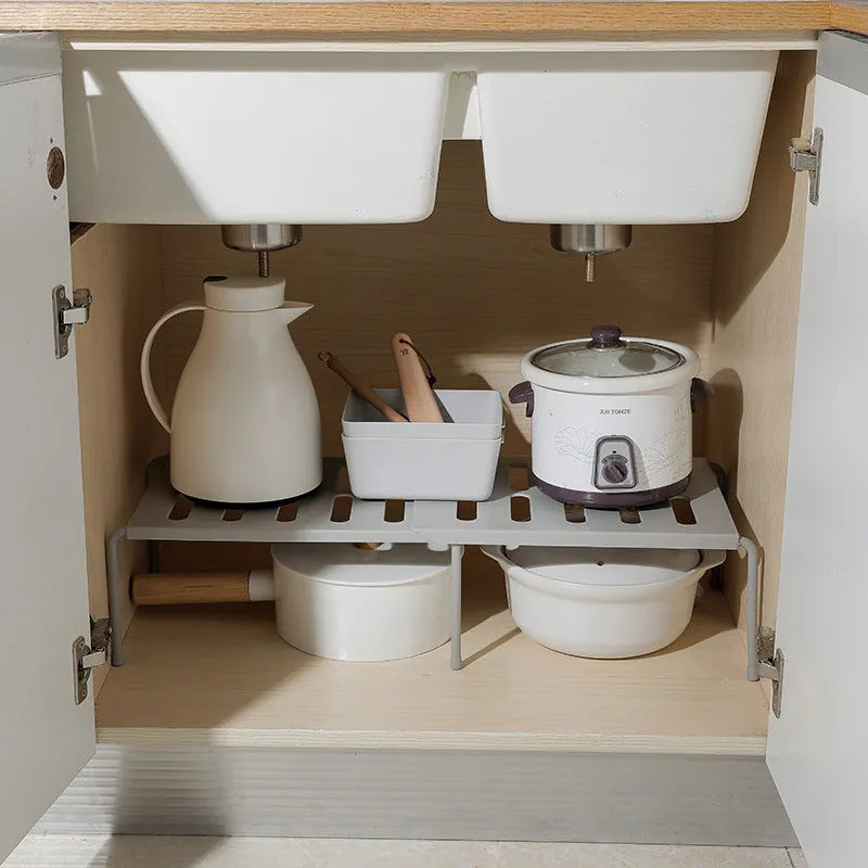 White telescopic plastic kitchen rack with single shelf, shown at adjusted height on a kitchen floor.