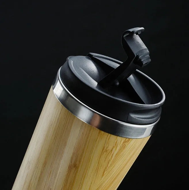 Bamboo travel coffee cup with stainless steel interior, leak-proof lid, and a grey foam pad.