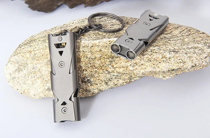 Compact metal keychain whistle with black lanyard on a keyring for outdoor emergency use