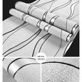 Roll of grey 3D stripe wallpaper with thick velvet texture next to a sample on a wall