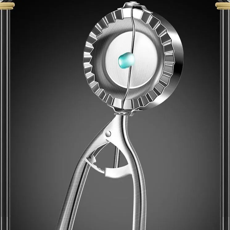 Silver stainless steel manual dumpling maker press tool on a kitchen surface.