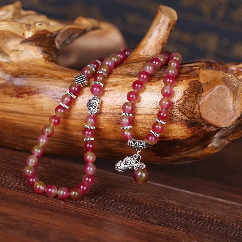 Handmade natural watermelon crystal bracelet with a Chinese knot, showing geometric beads in elephant style.