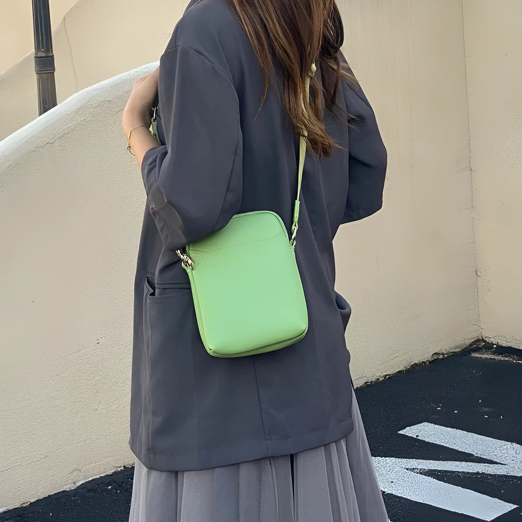 Solid colour small PU crossbody shoulder bag for mobile phones on a strap.