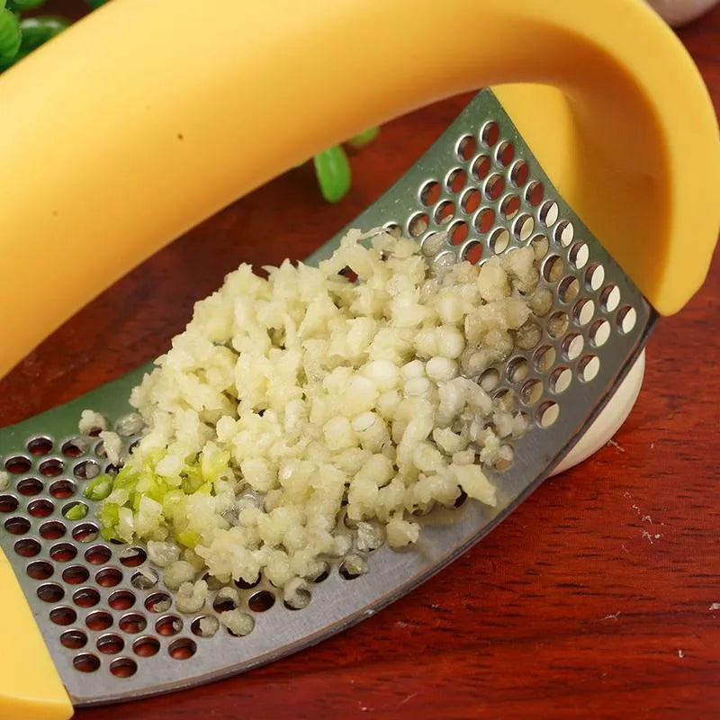 Stainless steel garlic press with ergonomic handle in assorted colours on a kitchen counter.