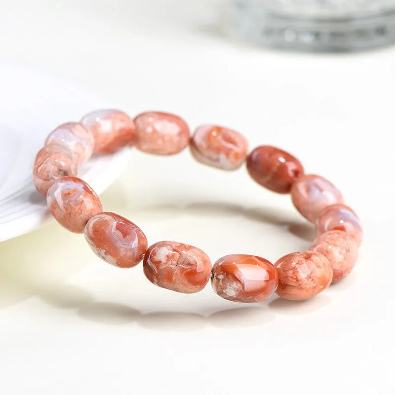 Natural cherry agate barrel bead bracelet with Ruyi symbols on a white background.