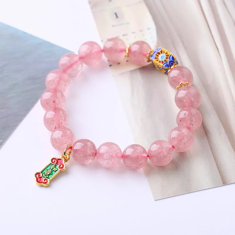 Close-up of a pink strawberry quartz crystal bracelet with hand-woven Ruyi design and letter detailing.