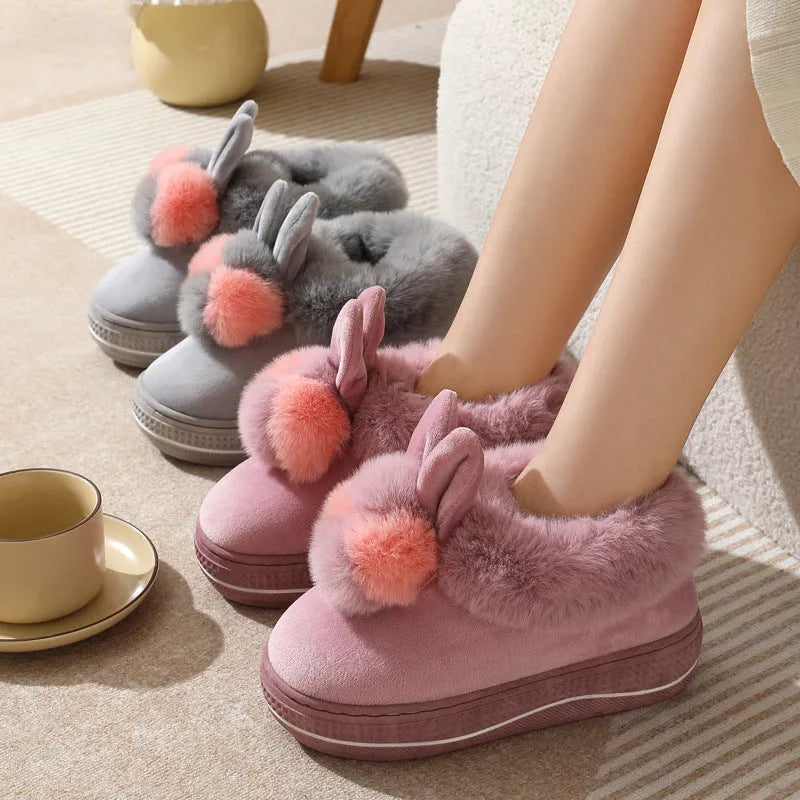 A pair of high-heel winter slippers with a plush fabric upper and a thick TPR sole.