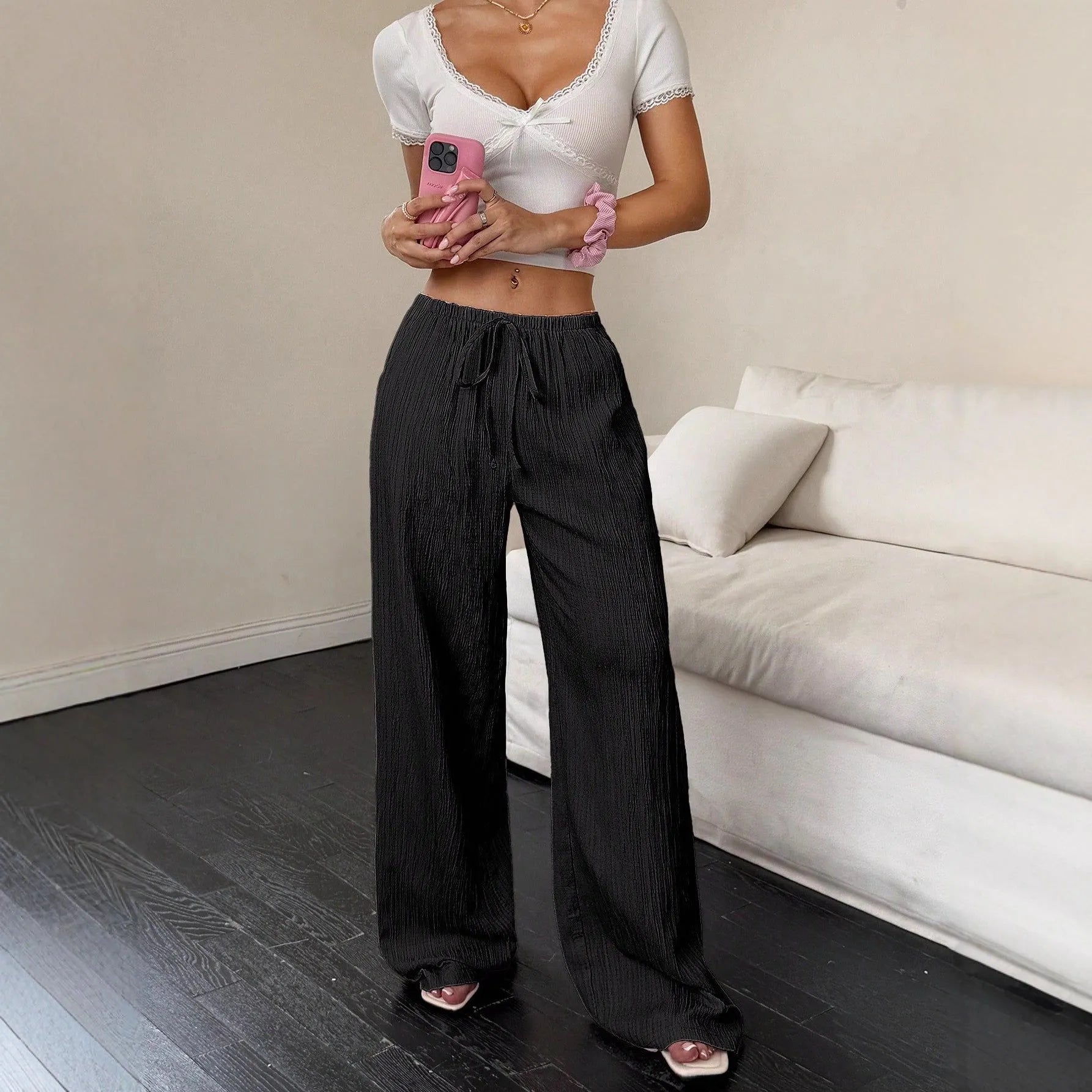 Women's black wide-leg trousers with a front lace-up detail on the waistband, laid flat.