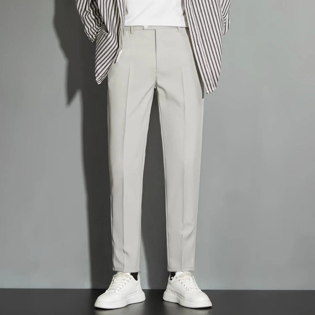 Men's straight-leg ankle-length suit trousers in a light colour showing drape and fit.