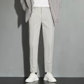 Men's straight-leg ankle-length suit trousers in a light colour showing drape and fit.