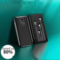 Portable power bank with digital display showing battery percentage, next to a smartphone and charging cables.