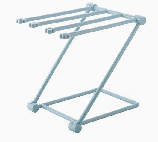 Light grey foldable plastic dishcloth shelf mounted on a wall holding towels.