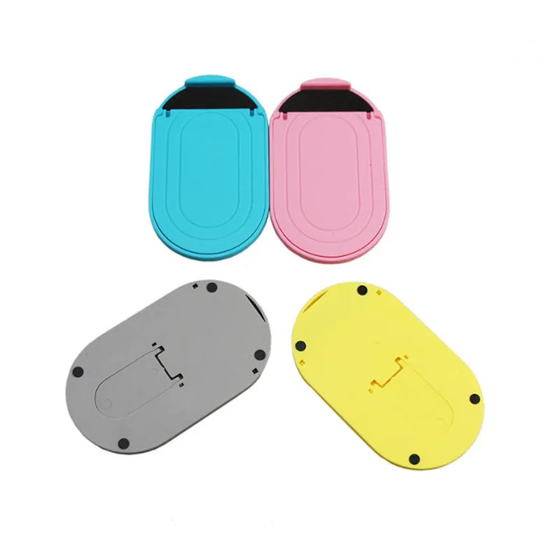 Plastic lazy bracket mobile phone stand in multiple colour choices on a table.