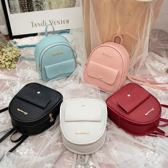Compact black PU leather women's shoulder backpack worn crossbody, showing zipper closure and simple design.