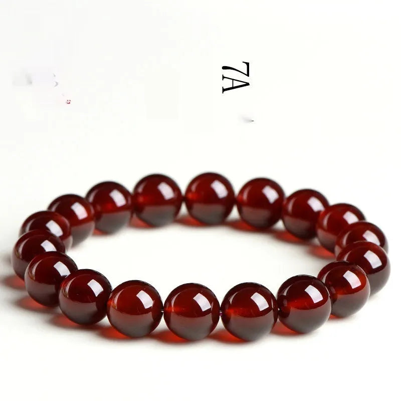 Natural orange red garnet crystal bracelet with ruyi design on a wrist.