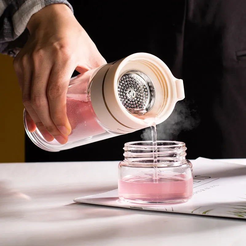 Green double-wall glass water bottle with a stainless steel tea infuser insert and a black leak-proof lid with rope handle.
