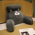 Large triangle-shaped reading cushion with embroidered design on a sofa.