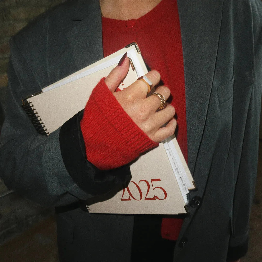 Cherry red daily schedule coil notebook with wire-o binding open on desk
