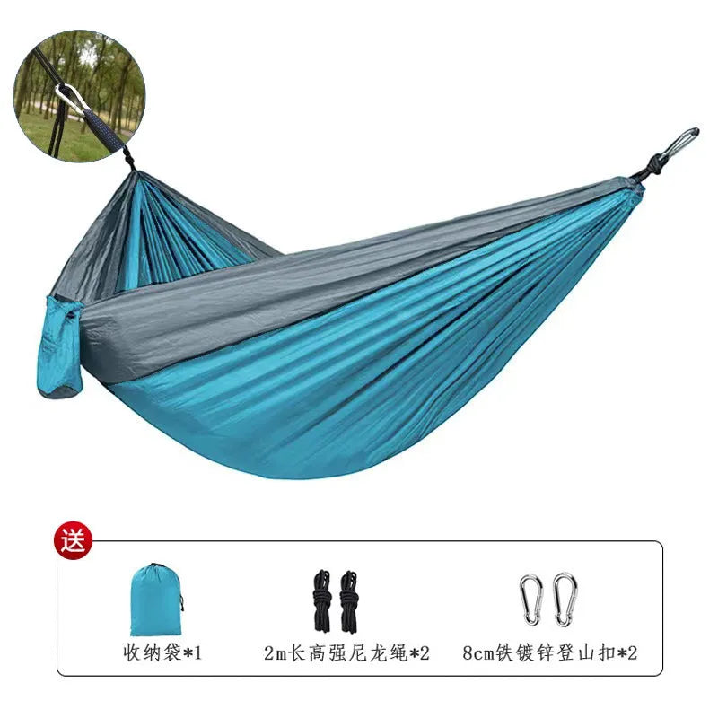 A sapphire blue parachute nylon hammock hung between two trees in a woodland setting.