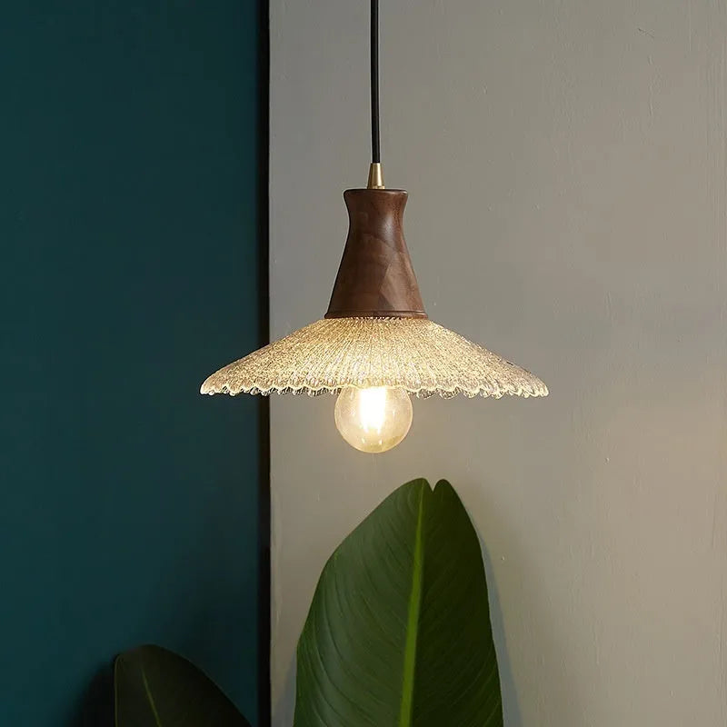 Retro chandelier with wooden body, brass metalwork, and a clear glass shade hanging from the ceiling.