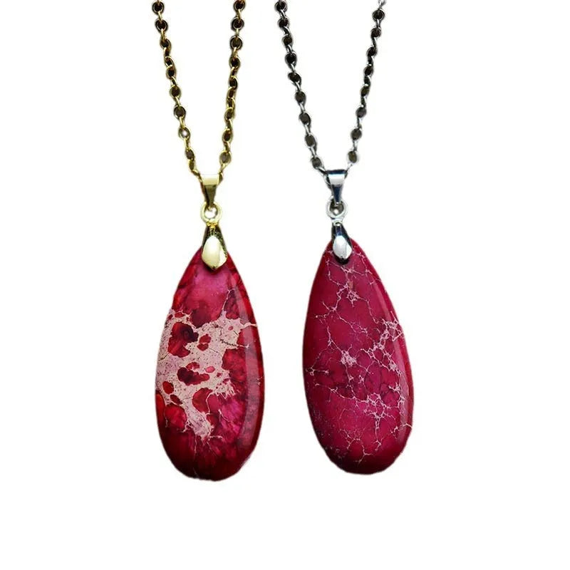 Close-up of an Emperor Stone necklace with a teardrop-shaped green jade pendant on a gold-plated chain, showing natural stone veining.