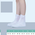 White high-top PVC reusable waterproof shoe covers for women on a wet surface.