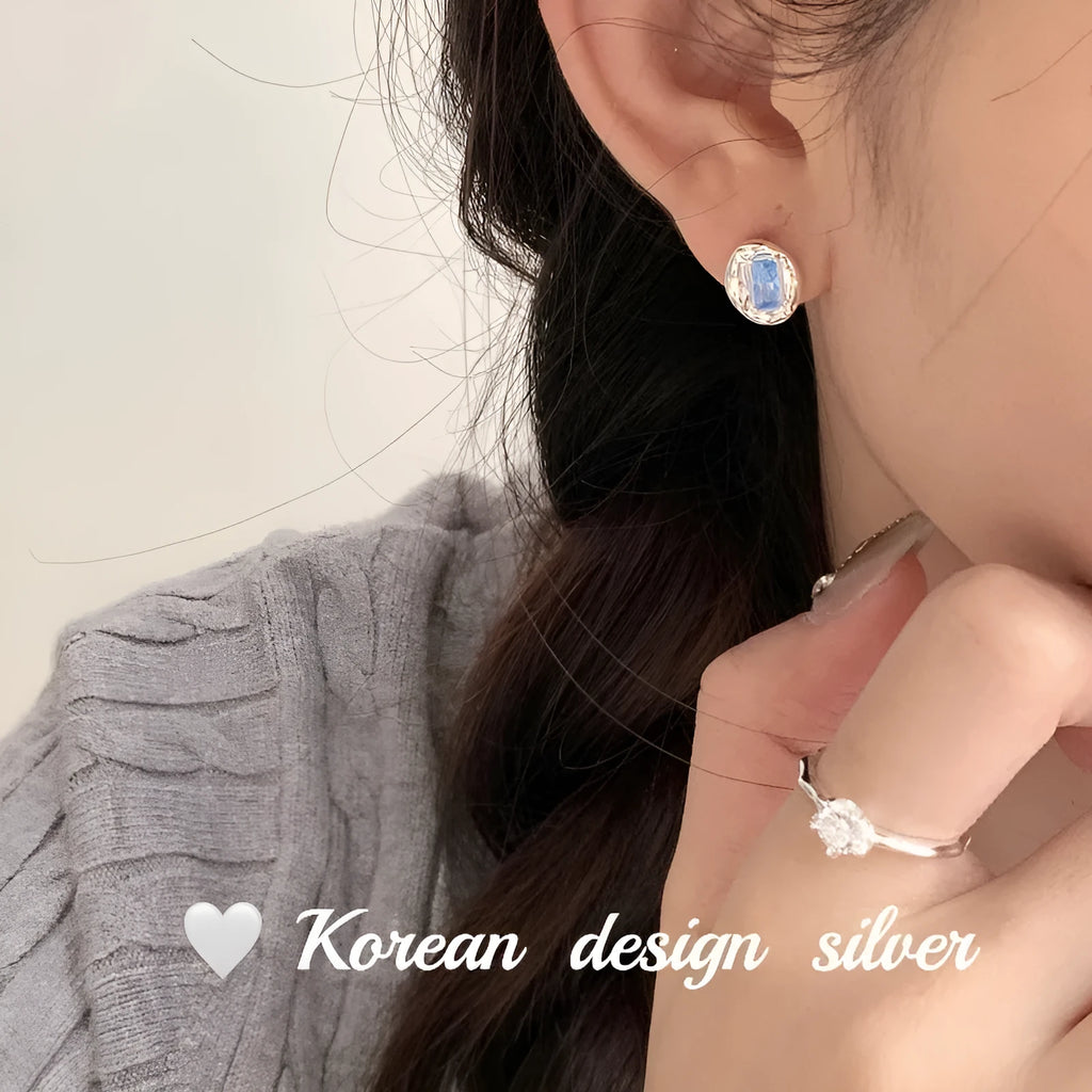 Women's sterling silver earrings with oval heart-wrapped design and blue diamond accents