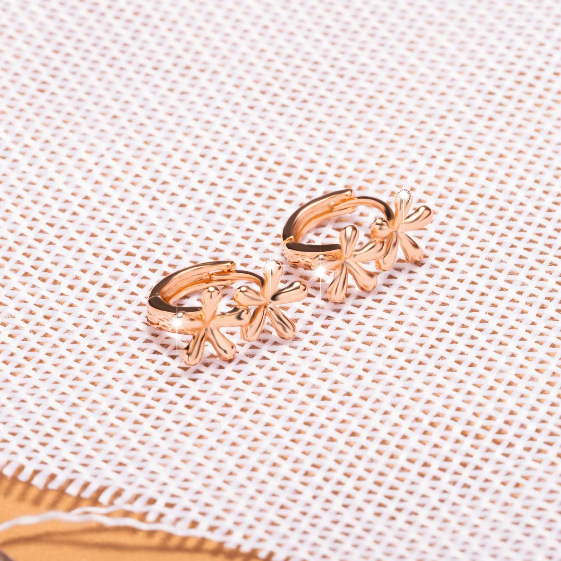 Silver rose gold electroplated circular waterdrop flower earrings with butterfly backs on a grey background.