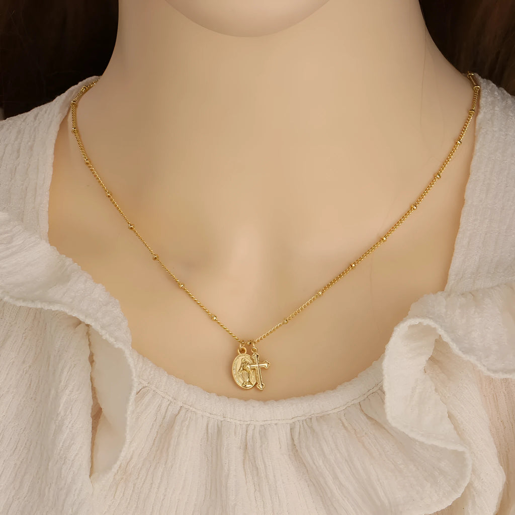 Geometric Virgin Mary cross pendant on a gold chain, showing simple design and 18K gold plating over copper.