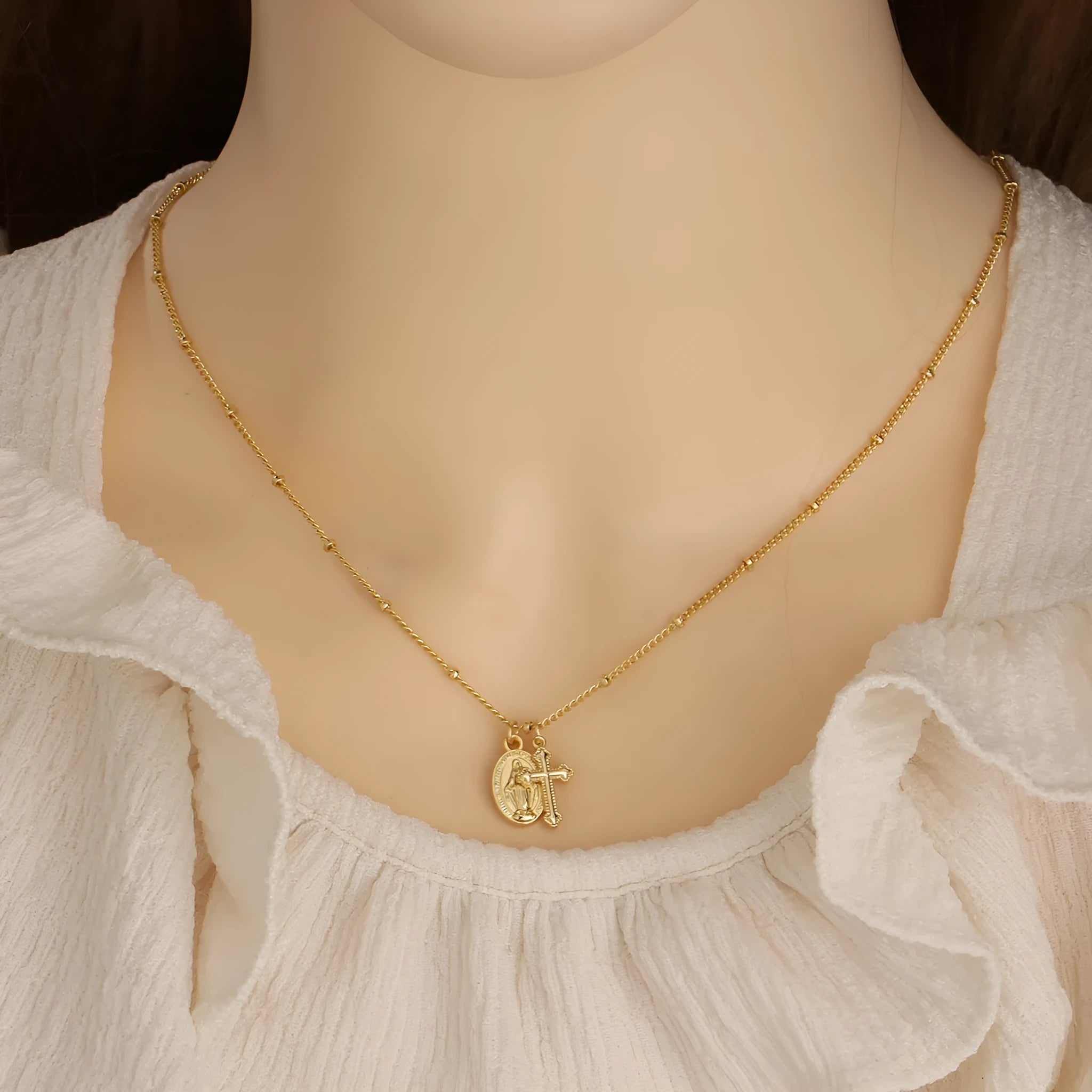 Geometric Virgin Mary cross pendant on a gold chain, showing simple design and 18K gold plating over copper.
