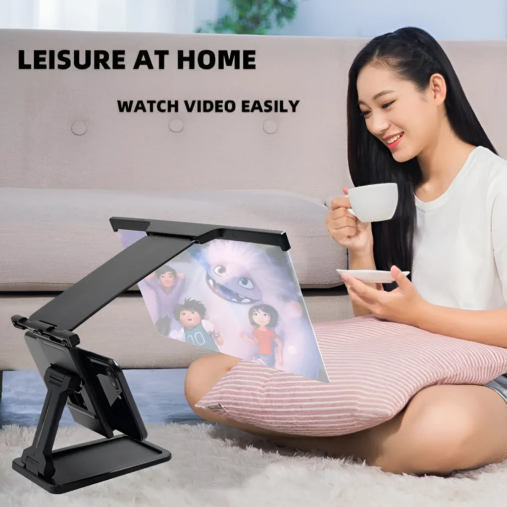 Black foldable mobile phone screen amplifier and detachable holder set up on a desk.