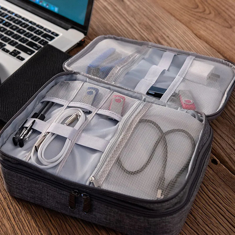 Grey waterproof electronics organiser bag with double-layer interior, handle, and zipper closure