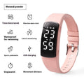 Black electronic digital watch with LED display and silicone strap on a wrist.