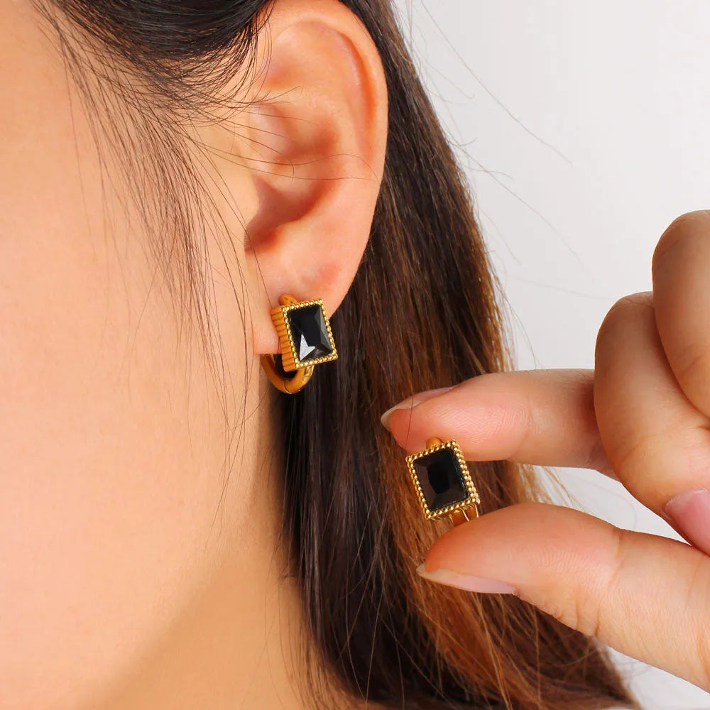 A pair of square-shaped stainless steel earrings with round zircon accents in a choice of black, green, or white.