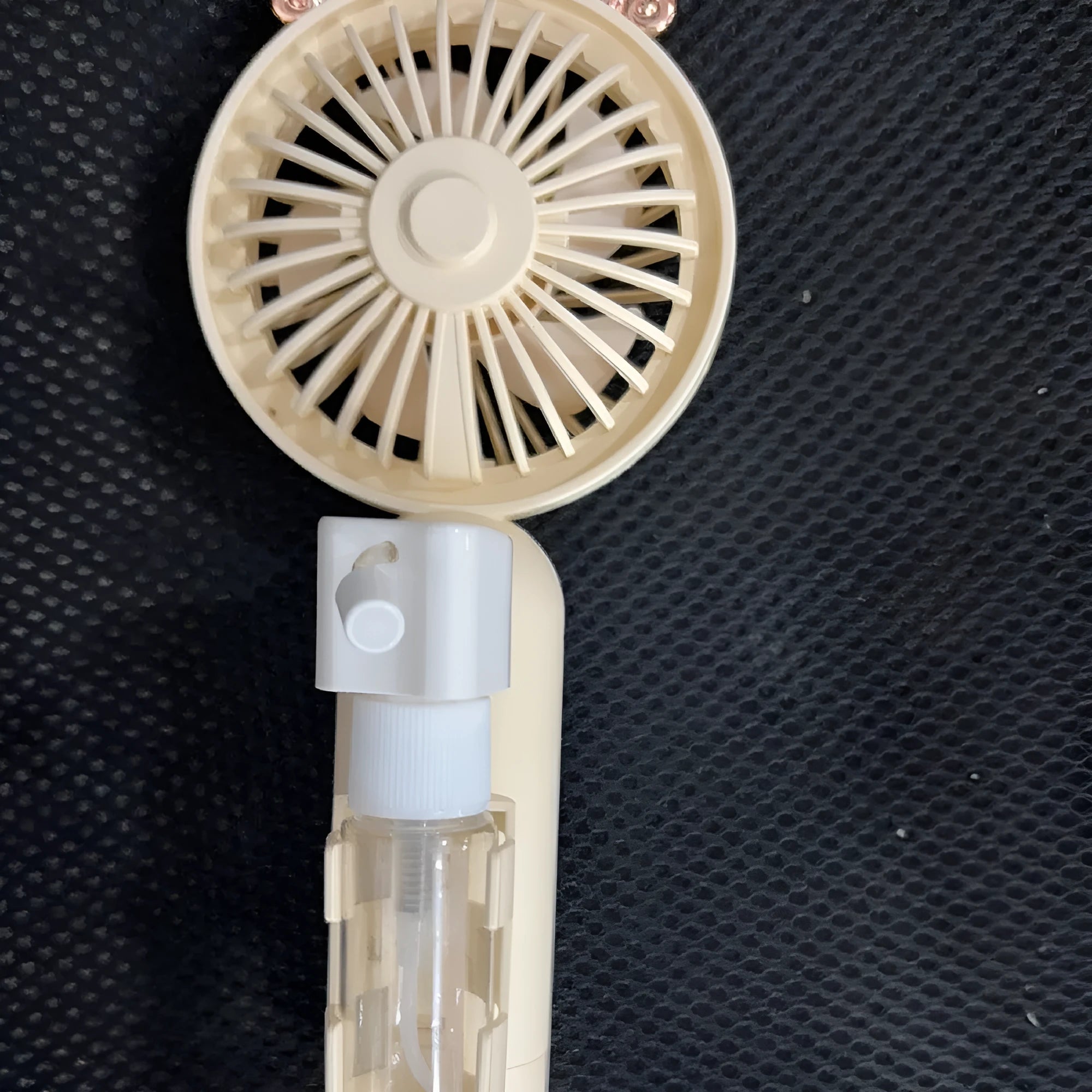 Compact plastic USB desk fan with a nozzle, shown in apricot colour on a desk.