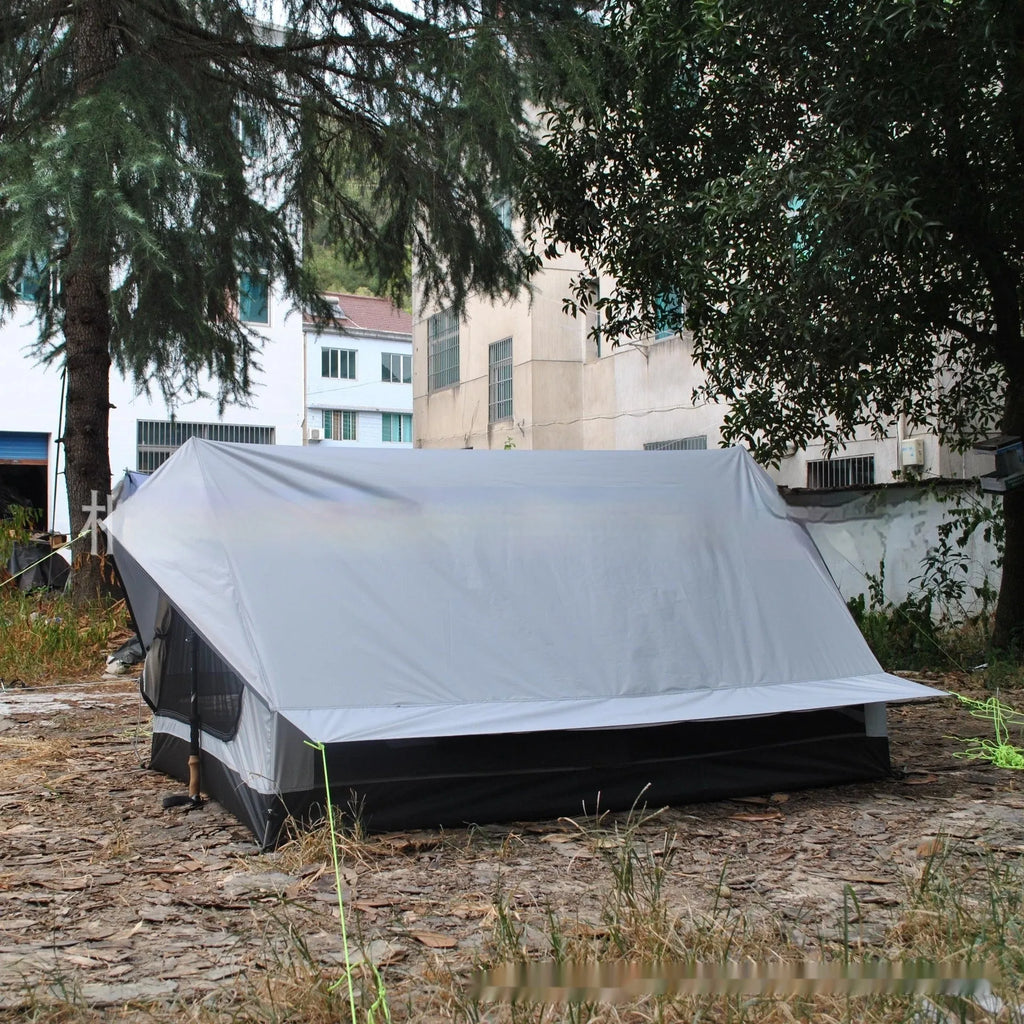 Brown A-Line pole-free cabin tent set up in a forest, showing its spacious interior for 2-3 people.