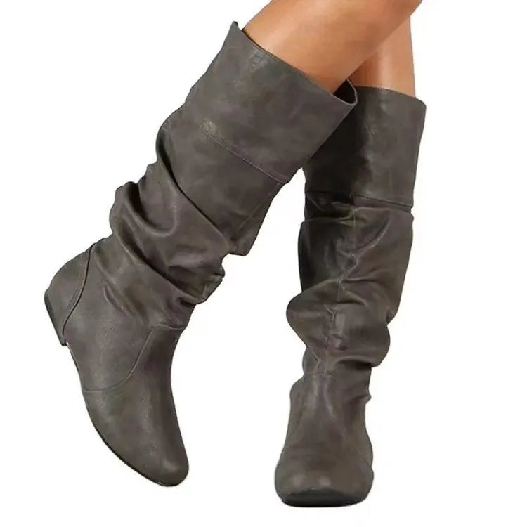 Women's black flat slip-on ankle boots with round toe and high cylinder cut, showing rubber sole.