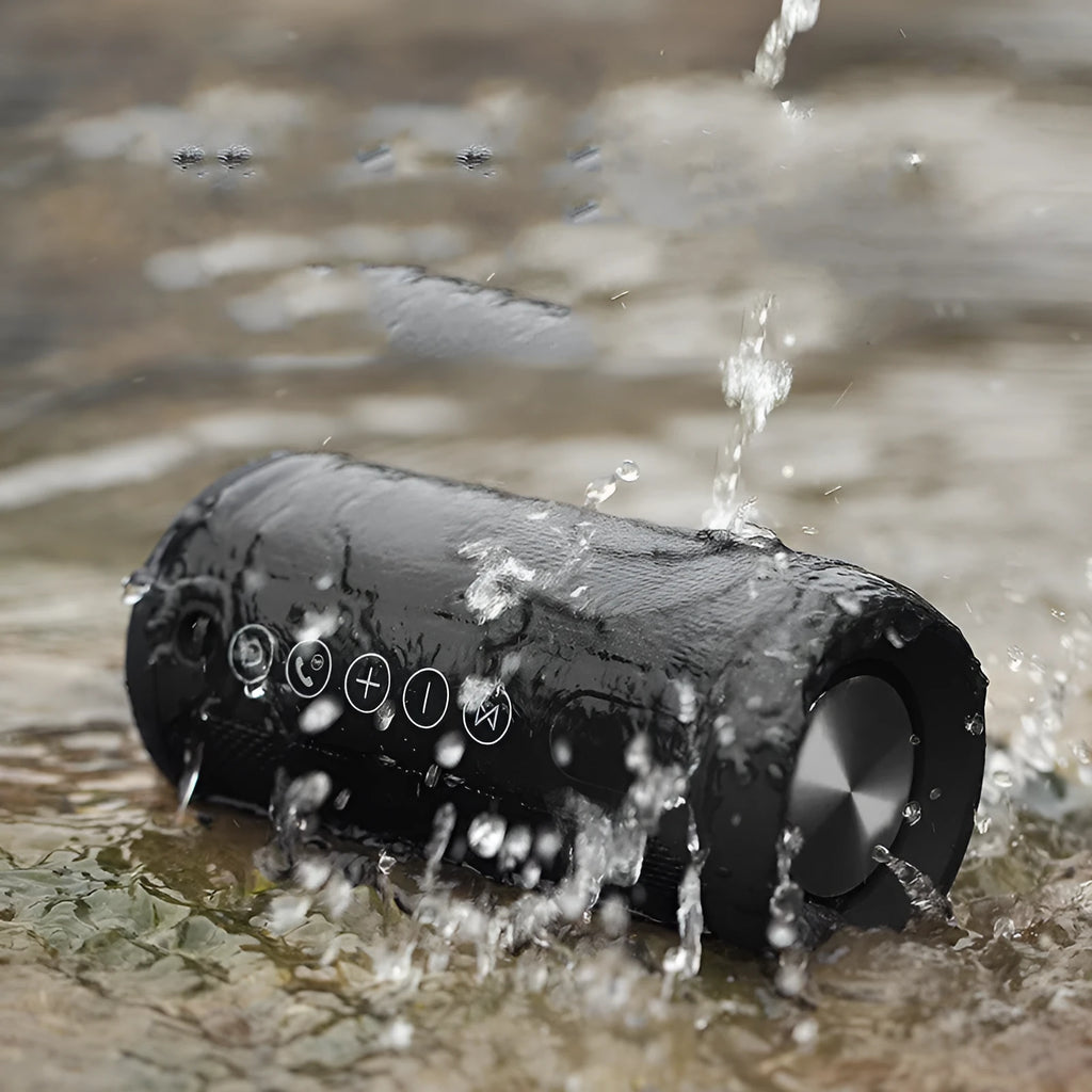 Compact portable outdoor Bluetooth speaker in camouflage finish, placed on a wooden garden table.
