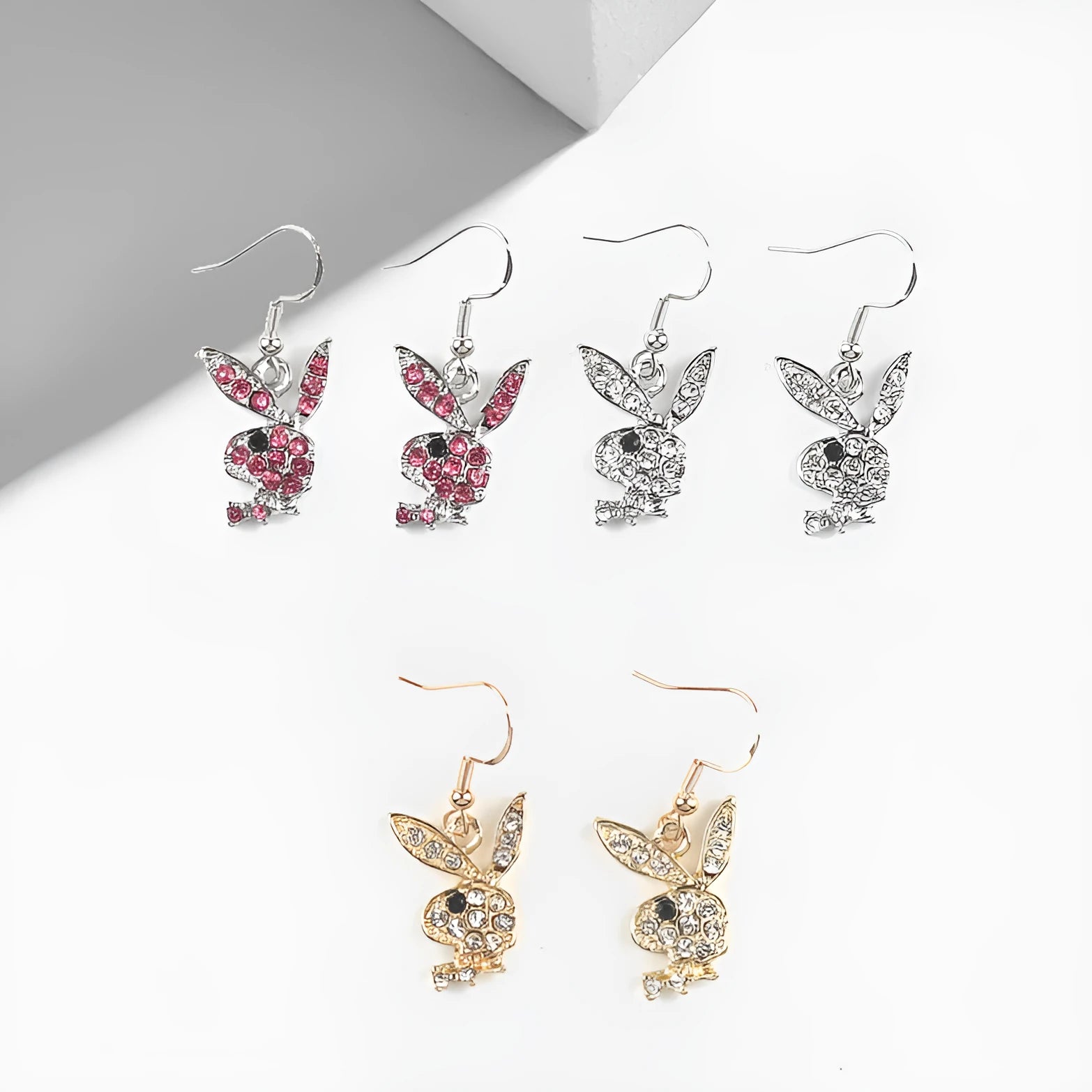 Close-up of a pair of small silver rabbit stud earrings with a sparkling rhinestone set in the centre on a white background.