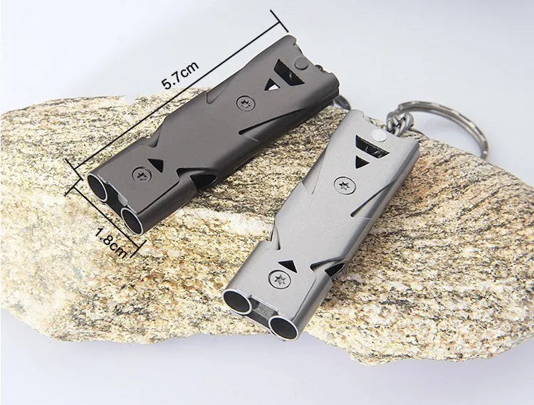 Compact metal keychain whistle with black lanyard on a keyring for outdoor emergency use