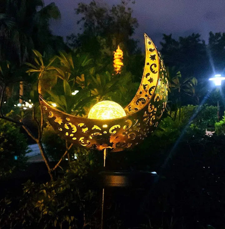LED solar flame light with warm white glow, iron construction, and glass globe in an outdoor garden setting